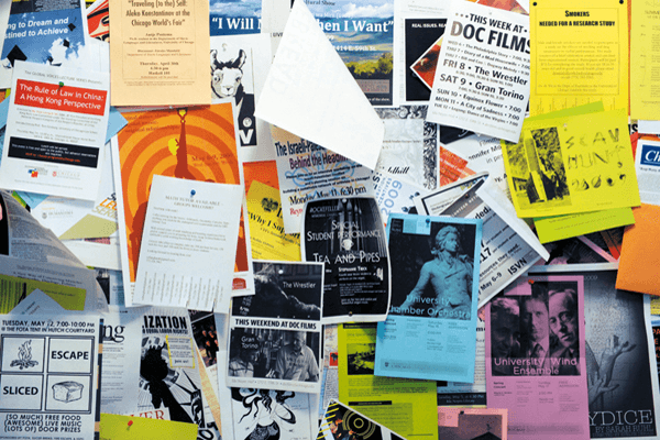 A campus bulletin board overflowing with club flyers, most invisible unless you already know to look